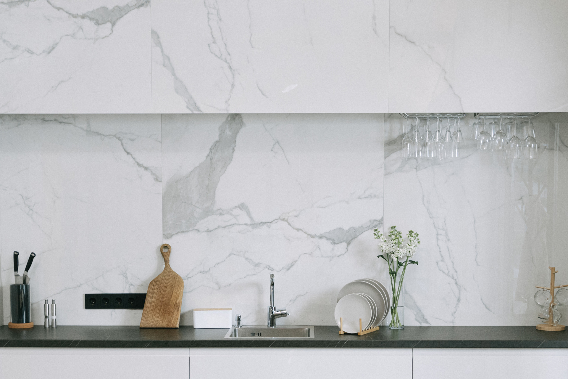 Foto de revestimiento de pared de cocina en marmol carrara. Cocina de colores claros, marmol blanco con vetas grises y elementos modernos de madera.